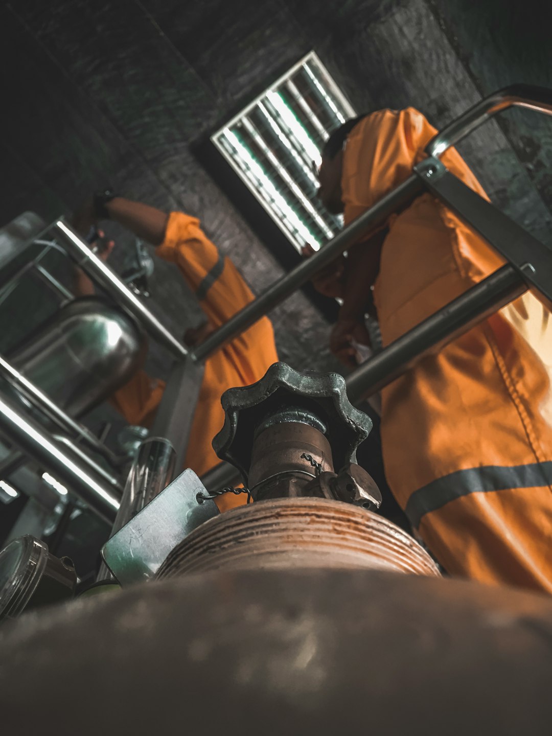 Industrial valve and piping installation with a worker in protective clothing
